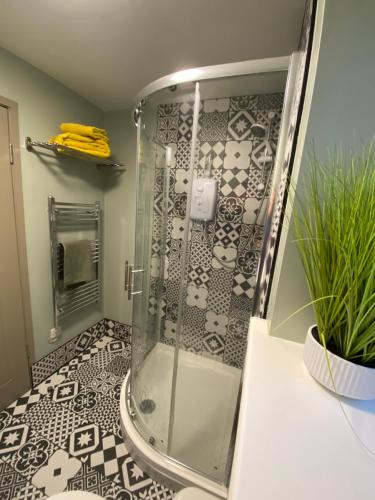 a bathroom with a shower with black and white tiles at Just the tonic in Nottingham