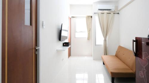 a living room with a couch and a window at Comfy 2BR Apartment at Puncak Kertajaya Surabaya near ITS By Travelio in Surabaya