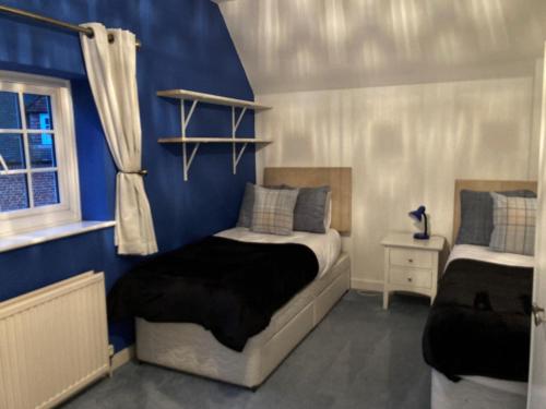 um quarto com uma cama e uma parede azul em Amazing 100 year old church Rectory em Brentwood