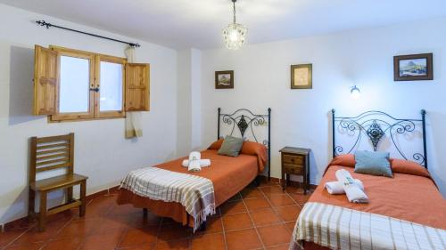 a bedroom with two beds and a chair and a window at Casa de Paquita Montefrio by Ruralidays in Montefrío
