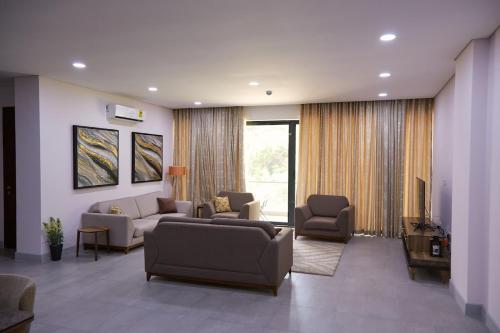 ein Wohnzimmer mit einem Sofa, Stühlen und einem TV in der Unterkunft Luxurious Penthouse With Luxurious Pool in Takoradi