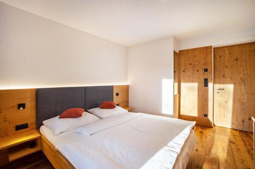 a bedroom with a large white bed and wooden floors at App Hubertus - Moosstock in Sand in Taufers
