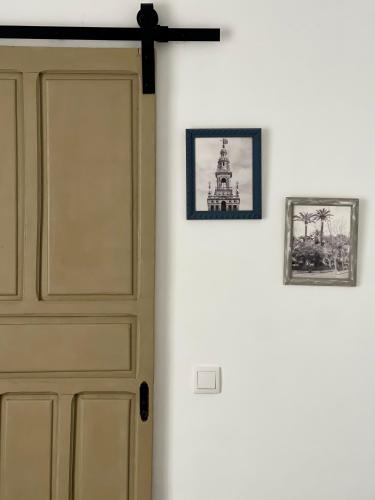 drzwi w pokoju z dwoma zdjęciami na ścianie w obiekcie Alojamientos El Carmen w mieście Écija