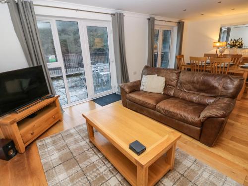 a living room with a brown leather couch and a table at Goldfinch in Milford Haven