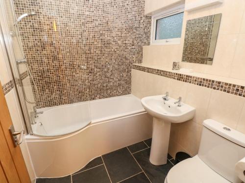 a bathroom with a tub and a sink and a toilet at Goldfinch in Milford Haven