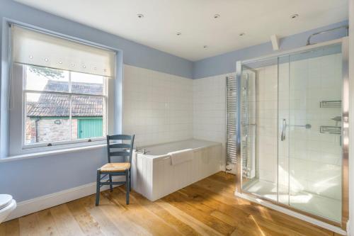 a bathroom with a tub and a shower and a chair at The Old Rectory in Bristol