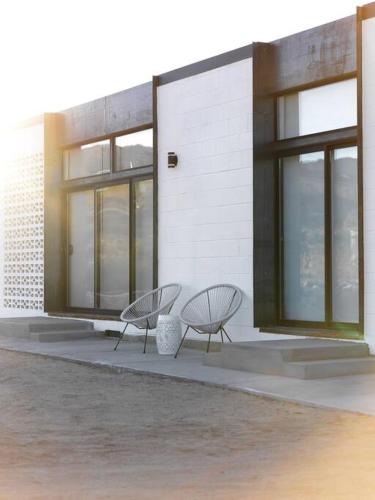 two chairs sitting in front of a building at Neutra Home Joshua Tree Luxury Retreat Pool and Spa in Joshua Tree