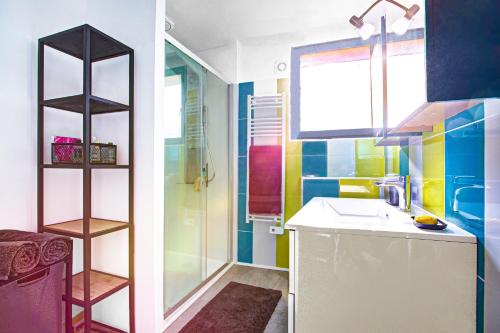 La salle de bains colorée est pourvue d'un lavabo et d'une douche. dans l'établissement Duplex Les Trois Ponts - Vue sur le Pont du Diable, à Céret