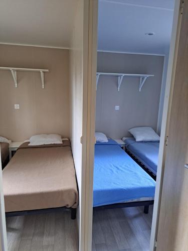 two beds in a small room with blue sheets at Camping Le Soulhol in Saint-Céré
