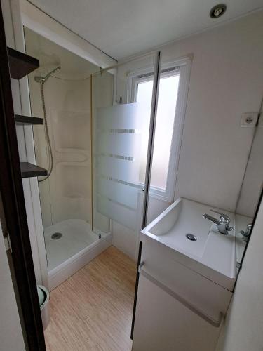 a white bathroom with a sink and a shower at Camping Le Soulhol in Saint-Céré