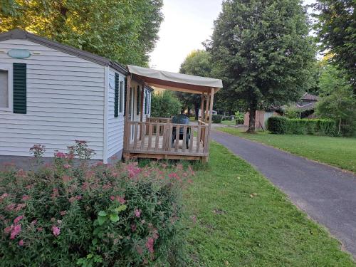 a house with a porch with a person sitting on it at Camping Le Soulhol in Saint-Céré