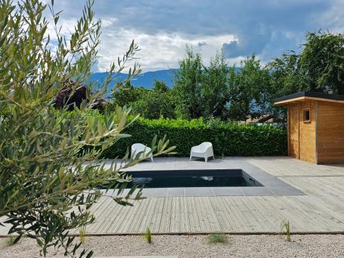 un patio trasero con una piscina con una silla y una mesa en Un moment de détente, en Gilly-sur-Isère