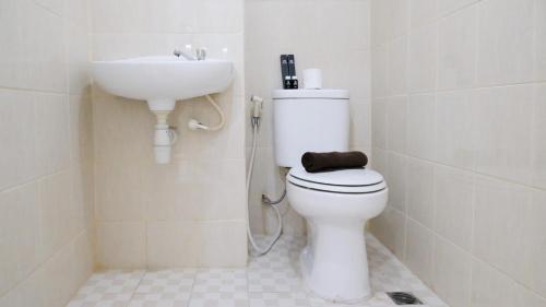 a bathroom with a white toilet and a sink at Best Choice 2BR at Puncak Permai Apartment Surabaya By Travelio in Surabaya
