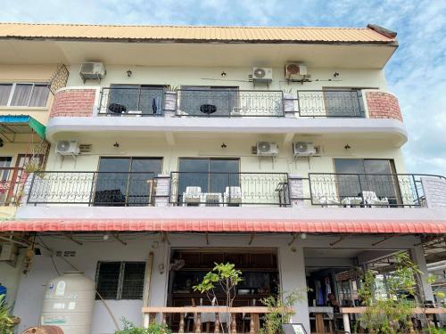 a building with balconies and tables and chairs at 2 Vikings Guesthouse in Karon Beach