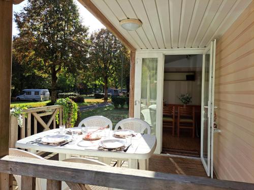 a white table with plates and bowls on a porch at Camping Le Soulhol in Saint-Céré