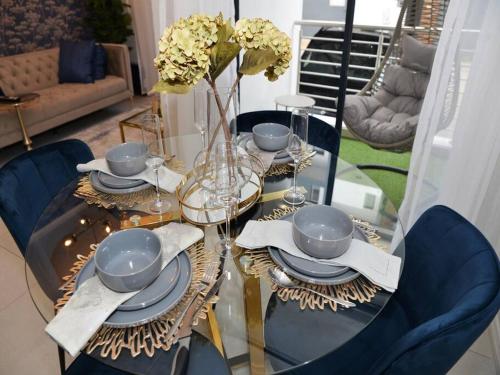 a dining room table with blue chairs and a table with plates and dishes at Elcaro Luxury Villas-Royal Abode in Midrand