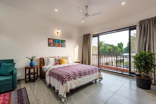 a bedroom with a bed and a balcony at SaffronStays Mayfair Gardens - 4BR pet-friendly pool villa with patio, den, board games & modern interiors near jetty in Alibaug