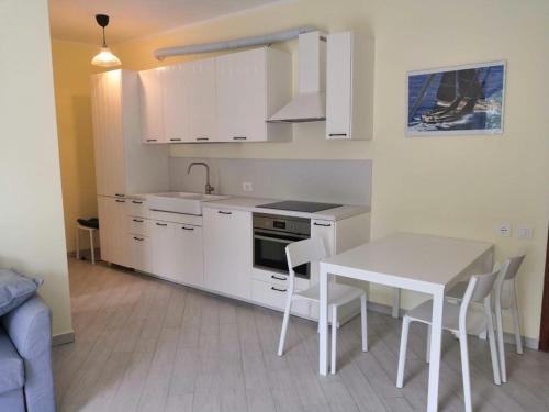 uma cozinha com armários brancos e uma mesa e cadeiras em D19 em Peschiera del Garda