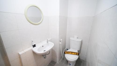 La salle de bains blanche est pourvue de toilettes et d'un lavabo. dans l'établissement Studio Apartment at Suncity Residence Sidoarjo near Suncity Mall By Travelio, à Sidoarjo