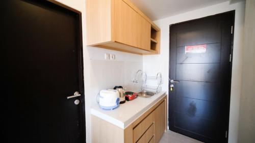 - une petite cuisine avec une porte noire et un comptoir dans l'établissement Studio Apartment at Suncity Residence Sidoarjo near Suncity Mall By Travelio, à Sidoarjo