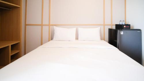 - une chambre avec un grand lit blanc et 2 oreillers dans l'établissement Studio Apartment at Suncity Residence Sidoarjo near Suncity Mall By Travelio, à Sidoarjo