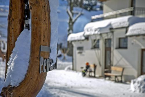 un panneau en bois avec de la neige devant une maison dans l'établissement Penzion Apidae, à Deštné v Orlických horách