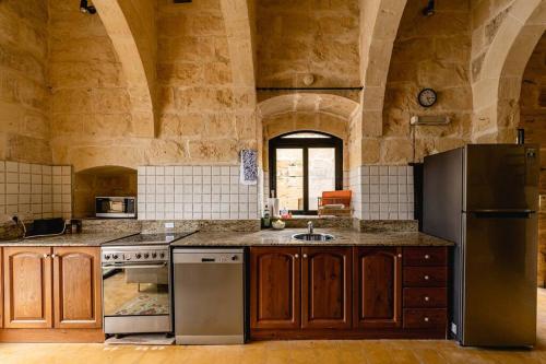 cocina grande con armarios de madera y nevera en Charming & Stylish Historic Farmhouse with Pool, en Xewkija