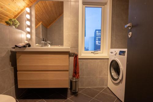 a bathroom with a sink and a washing machine at Urban and stylish apartment in city centre in Tromsø