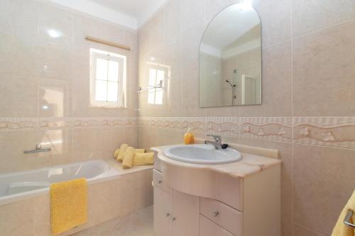 a bathroom with a sink and a tub and a mirror at Casa Anton in Carvoeiro