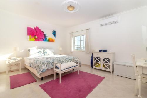 a white bedroom with a bed and a pink rug at Casa Anton in Carvoeiro