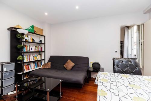 un salon avec un canapé et une étagère dans l'établissement JOLI et LUMINEUX T1 33 m dans un quartier calme, à Paris