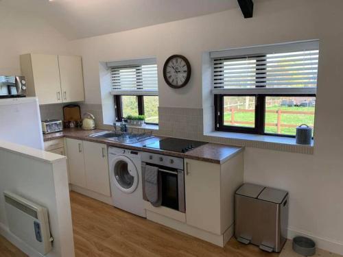 a kitchen with a washing machine and a clock on the wall at Cosy & Characterful, Seaside Cottage, Dog Friendly in Worle