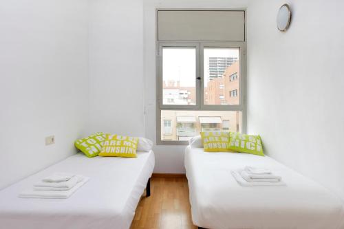 2 weiße Betten in einem Zimmer mit Fenster in der Unterkunft 1223 - POBLENOU APARTMENT in Barcelona