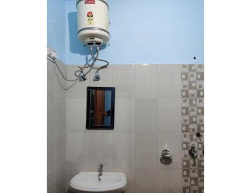 baño con aseo y una luz sobre un lavabo en Hotel Hans Deep, Phata en Phata