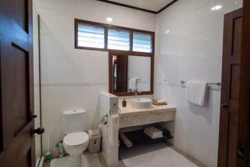 a bathroom with a toilet and a sink and a mirror at Nongsa Village in Nongsa