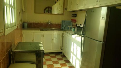 a kitchen with white cabinets and a refrigerator at Farm dream in Al Rahba