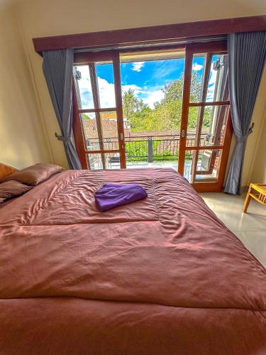 a bedroom with a large bed with a large window at Ojek's Homestay in Ubud