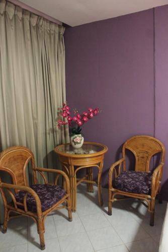 a room with two chairs and a table with a vase of flowers at B-Home Residence in Patong Beach