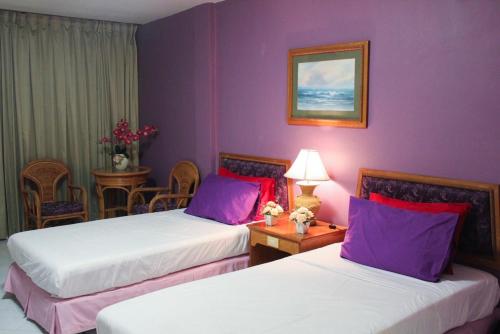 two beds in a hotel room with purple walls at B-Home Residence in Patong Beach