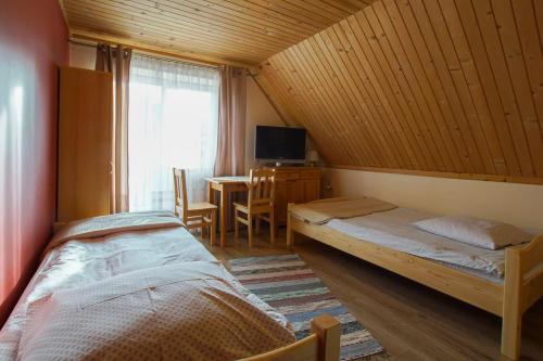 ゾンプにあるPokoje u Rumcajsaのベッドルーム1室(ベッド2台、窓付きテーブル付)