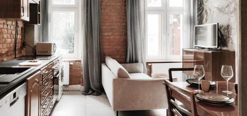 uma cozinha com um sofá e uma mesa com copos de vinho em Mini dwupokojowy apartament vintage 23m2 em Poznań