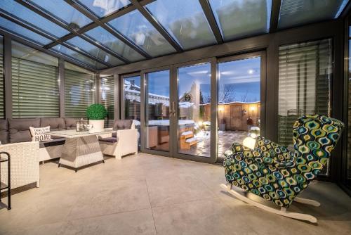 Rodzinny stylowy dom z jacuzzi في ميلنو: حديقة شتوية بسقف زجاجي مع طاولة وكراسي