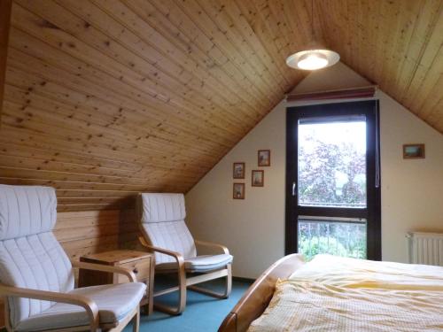 1 dormitorio con 2 sillas, 1 cama y 1 ventana en Ferienhaus Heisch, en Schafflund