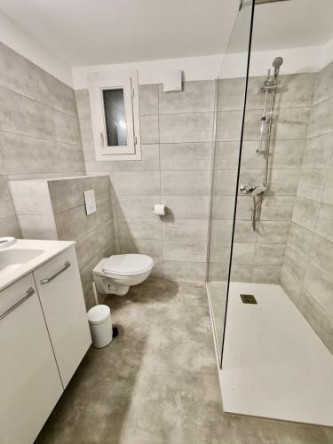 une salle de bain avec toilettes et douche en verre dans l'établissement Résidence hôtelière les hameaux de saint cyprien appartement 35 M2 1 chambre, à Lecci