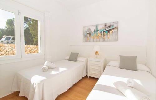 2 Betten in einem weißen Zimmer mit Fenster in der Unterkunft Villa Jomar by Sonne Villas in Cala Galdana