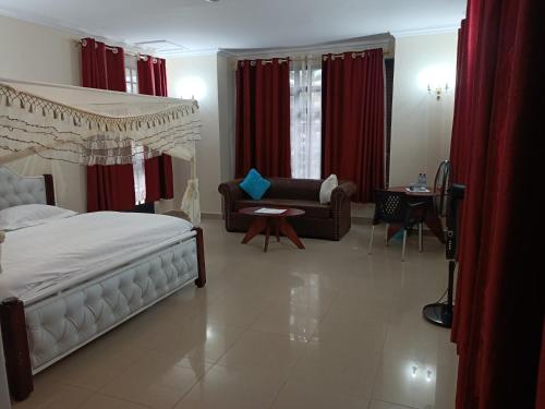 a bedroom with a bed and a couch and red curtains at Amigo apartments in Kisumu