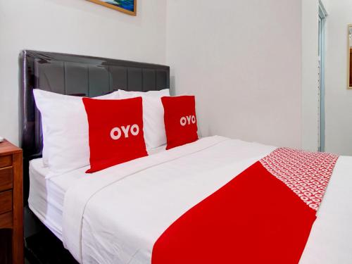 a red and white bed with two red pillows at OYO 93188 Soren Hotel And Coffee in Lawean