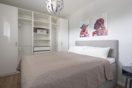 a white bedroom with a bed and a chandelier at Park-Apartment Scharmützelsee Wohnung 12 in Wendisch Rietz