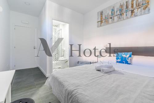 a white bedroom with a bed with a hotel sign on the wall at AYZ Ulises - Auto check-in property in Madrid