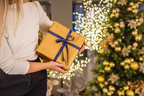 a woman holding a present in front of a christmas tree at Du Lac Et Du Parc Grand Resort in Riva del Garda